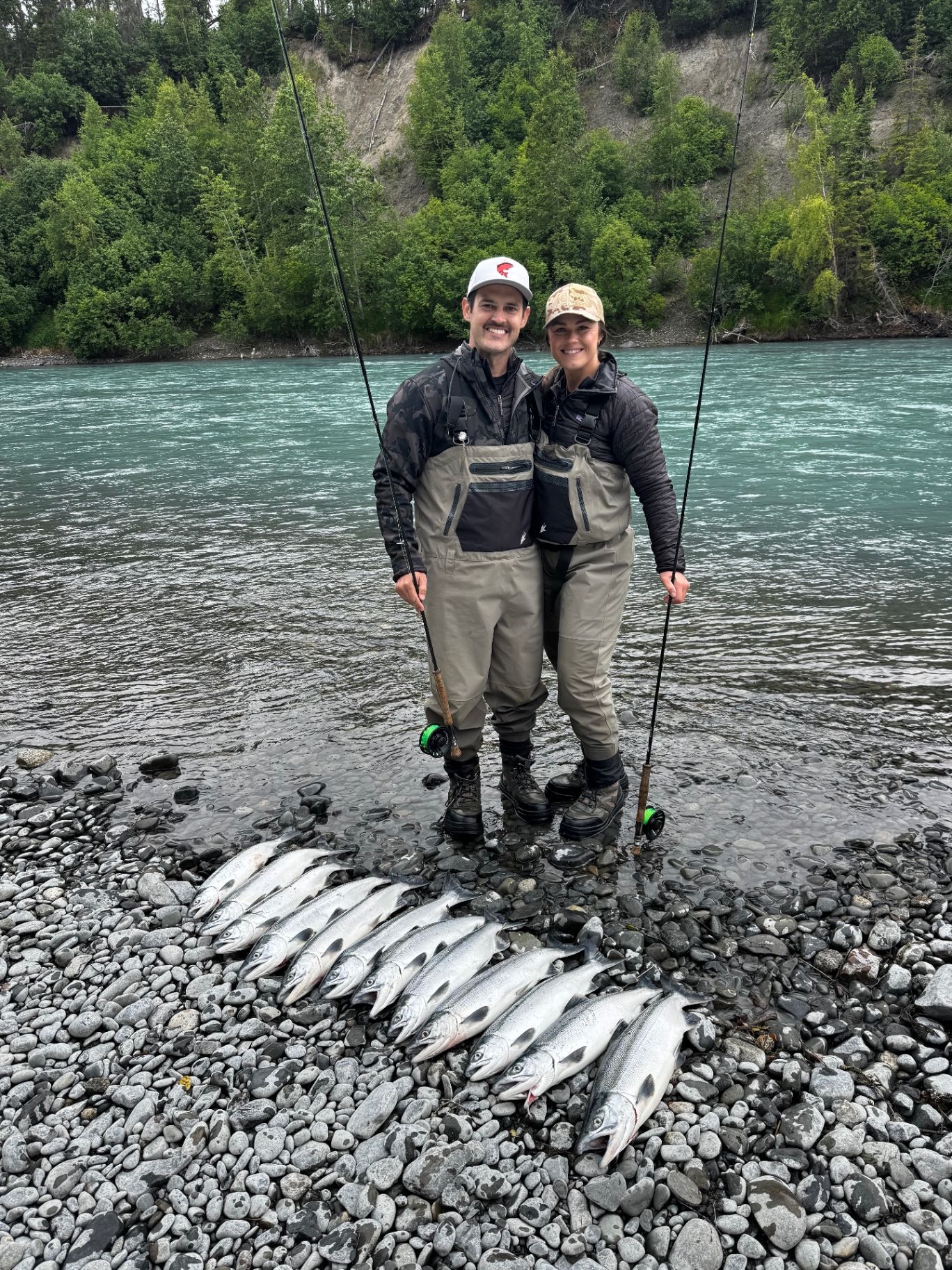 Couple posing with their salmon catch on the riverbank