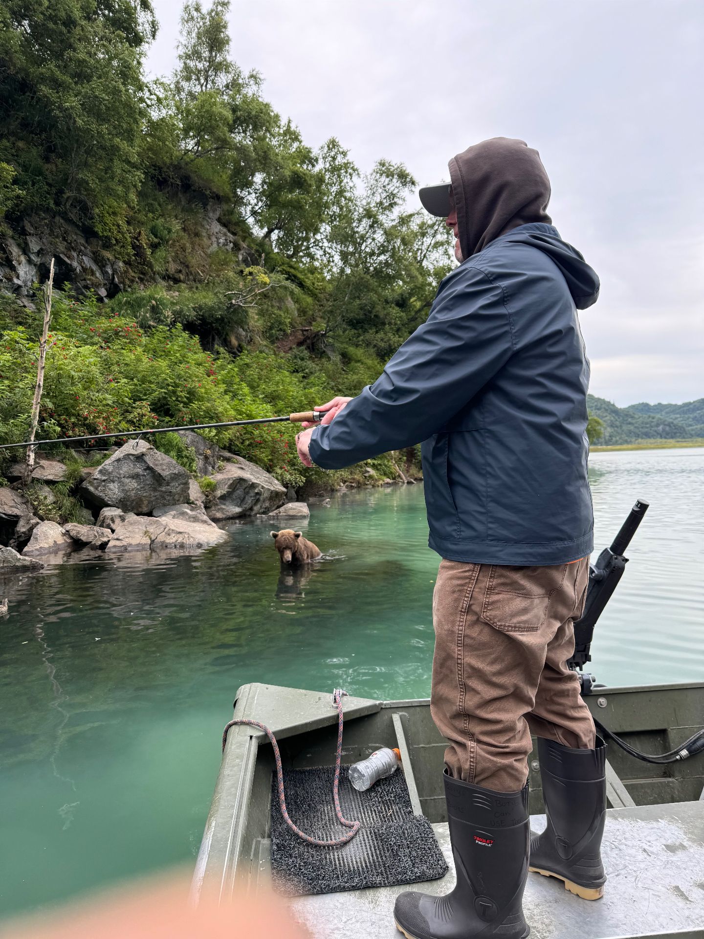 Angler fishing just feet away from a brown bear in the water