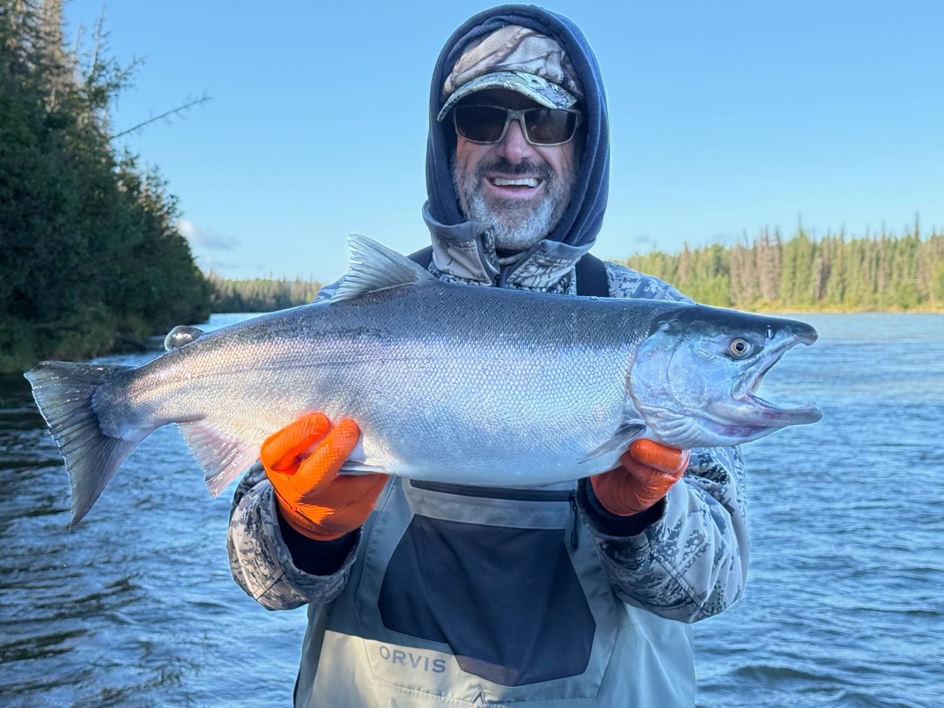 Angler holding a large salmon with orange gloves