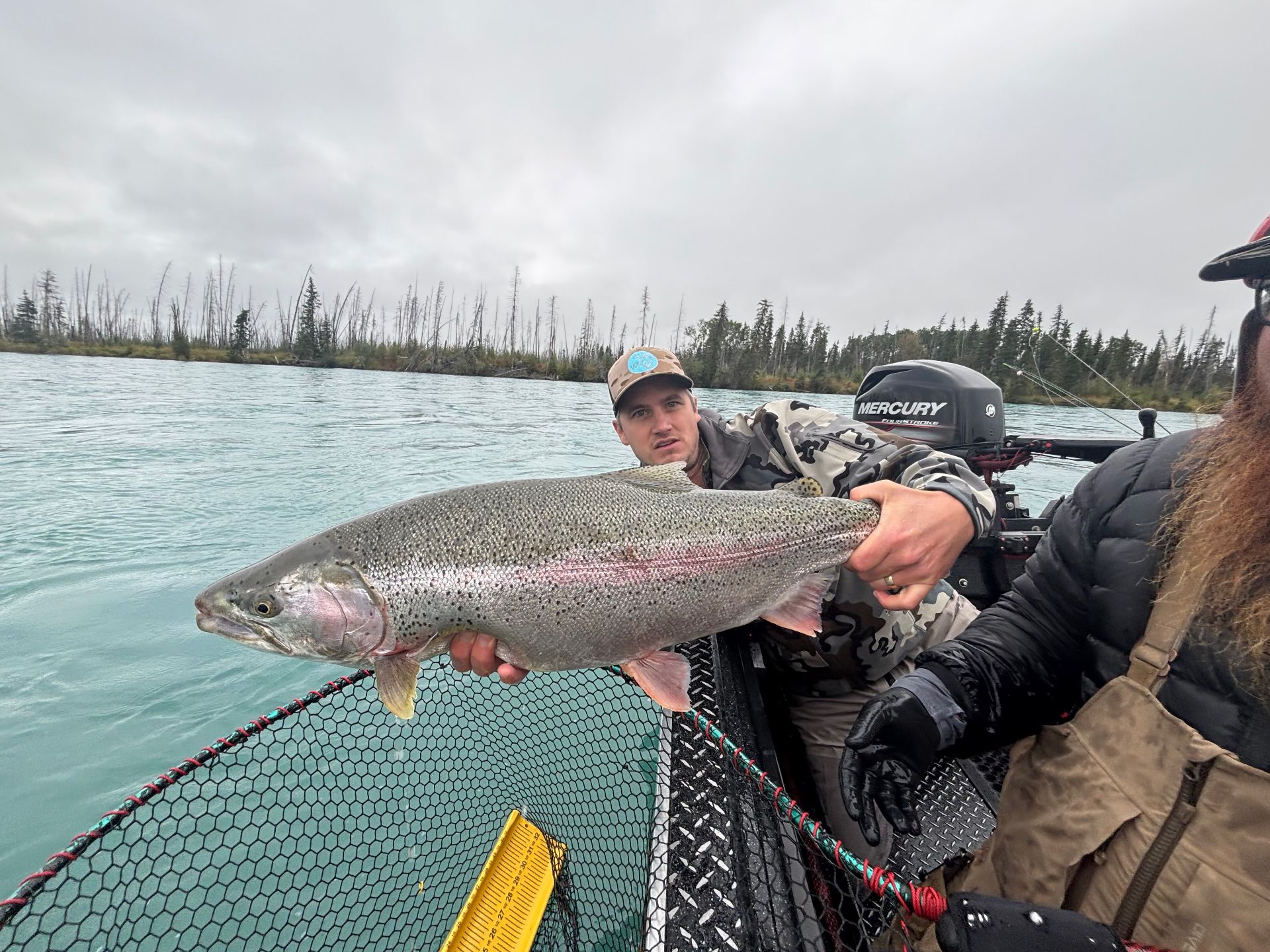 Angler holding a trophy rainbow trout from the motor boat on the Kenai River